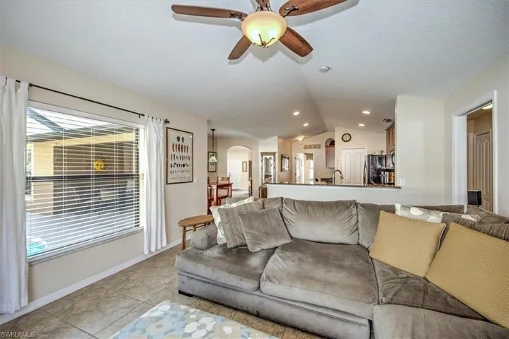 Tiled living room featuring vaulted ceiling, sink, and ceiling fan