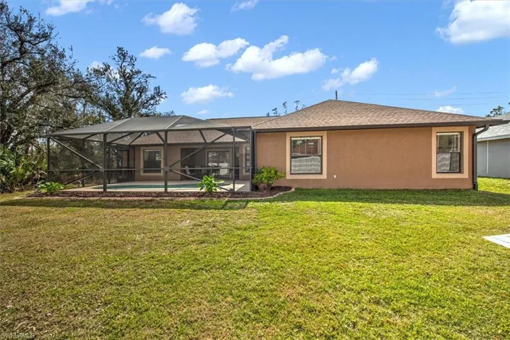 Back of property featuring a yard and a lanai