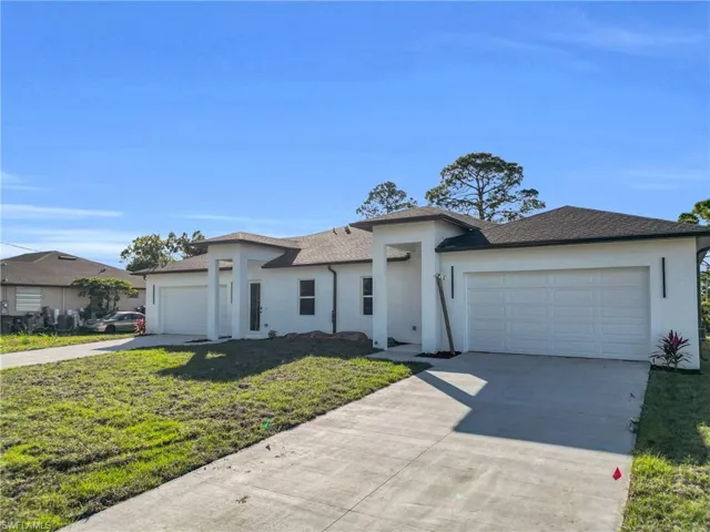 Prairie-style home featuring a garage, concrete driveway, a front lawn, and stucco siding