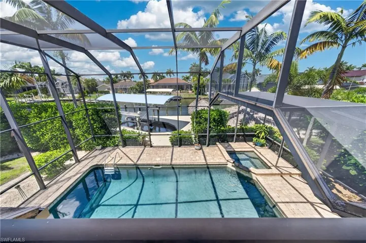 The property features a screened-in pool area with an integrated spa, surrounded by a paved deck