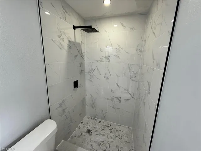 Bathroom with tiled shower and a textured wall
