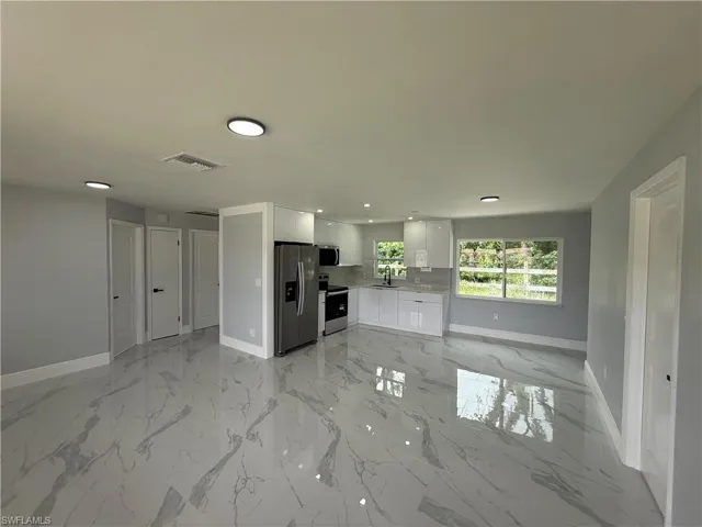 Unfurnished living room featuring light marble finish flooring and recessed lighting