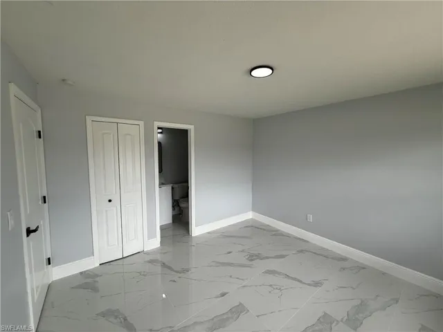 Unfurnished bedroom featuring light marble finish flooring and a closet