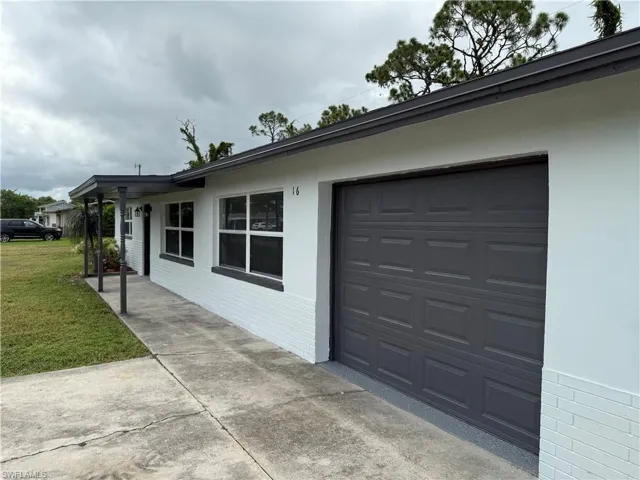 View of home's exterior featuring a garage, concrete driveway, a yard, and stucco siding