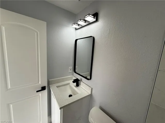 Half bath featuring a textured wall and vanity