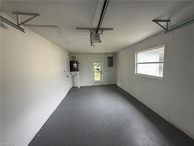 Garage with electric panel, water heater, and a garage door opener