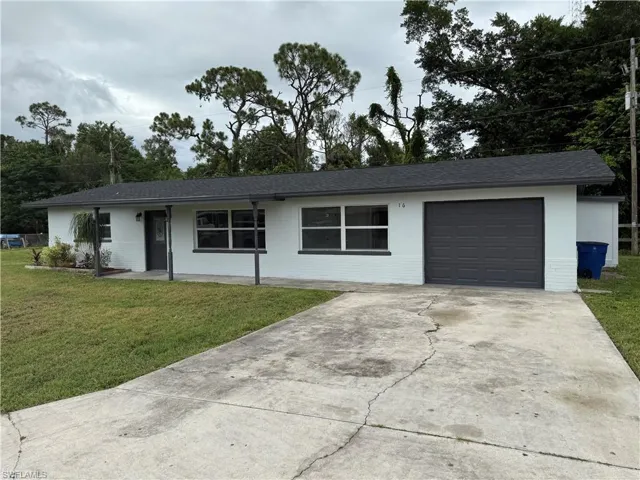 Single story home featuring concrete driveway, a front yard, and an attached garage