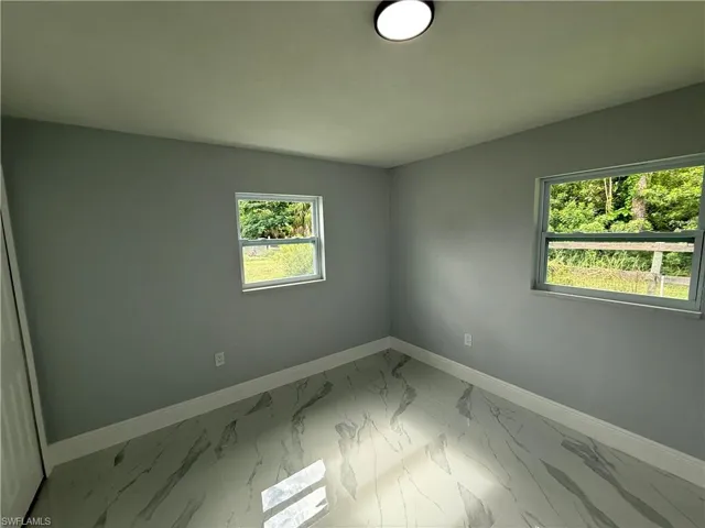 Empty room featuring baseboards and light marble finish floors