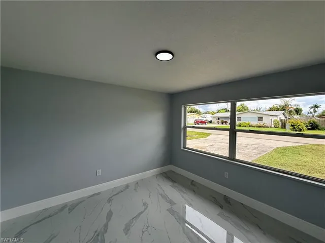 Unfurnished room featuring light marble finish flooring and a residential view
