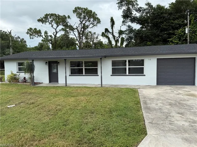Single story home with driveway, a front yard, an attached garage, and a shingled roof