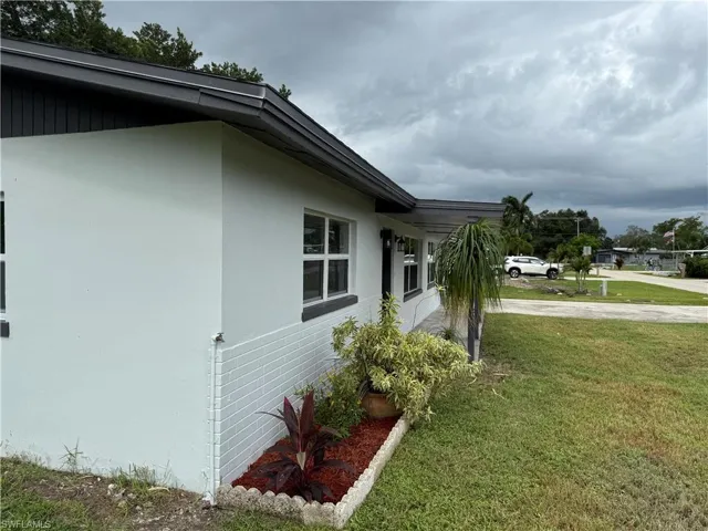 View of property exterior featuring stucco siding, a lawn, and driveway