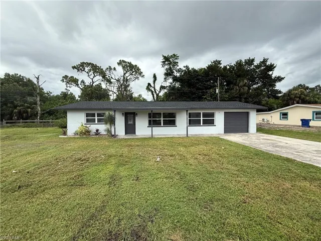 Single story home featuring a front lawn, driveway, and an attached garage