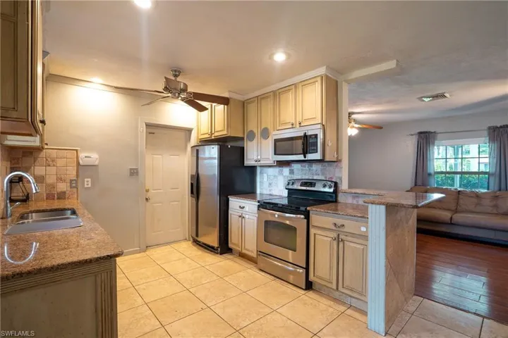 Kitchen featuring ceiling fan, tasteful backsplash, stainless steel appliances, light tile floors, and sink