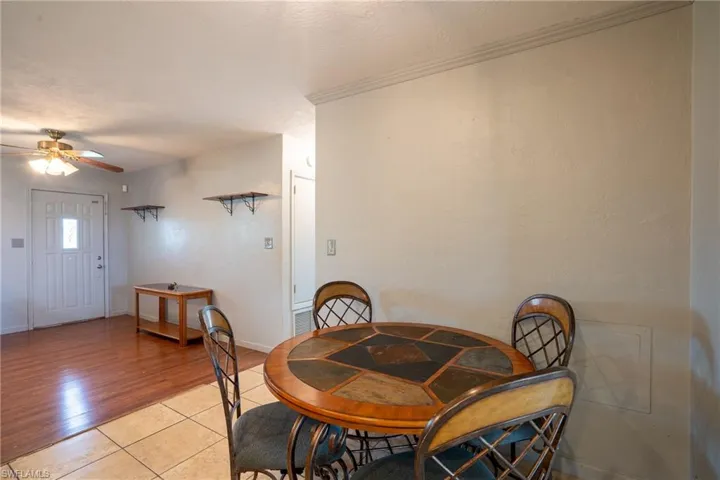 Dining room with ceiling fan, crown molding, and light tile flooring