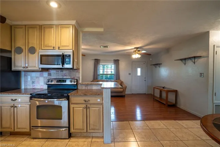 Kitchen featuring backsplash, appliances with stainless steel finishes, ceiling fan, and light tile floors