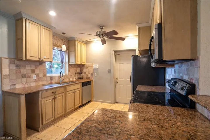 Kitchen featuring ceiling fan, tasteful backsplash, stainless steel appliances, decorative light fixtures, and sink