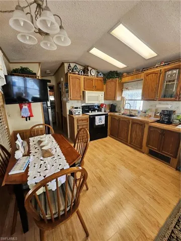 Kitchen featuring brown cabinetry, black / electric stove, light wood-style floors, and a sink
