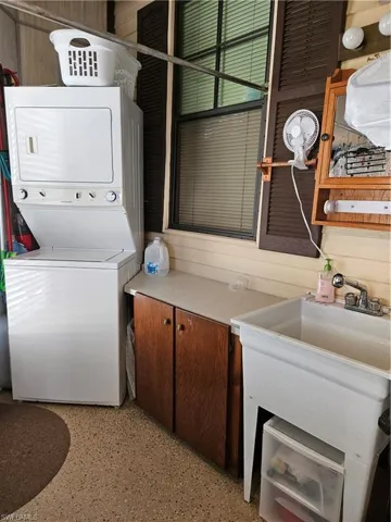 Laundry area featuring cabinet space, wood walls, and stacked washing maching and dryer