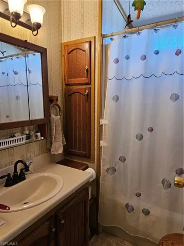 Bathroom with wallpapered walls, vanity, and a shower with curtain