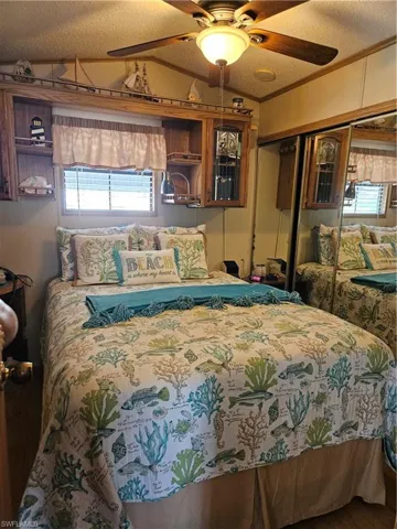 Bedroom with ornamental molding, a ceiling fan, a textured ceiling, a closet, and vaulted ceiling