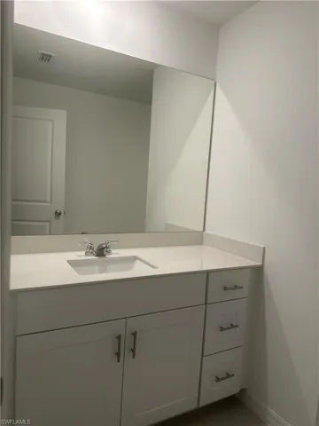 White vanity with shaker-style cabinetry, a built-in rectangular sink, and a light-toned countertop