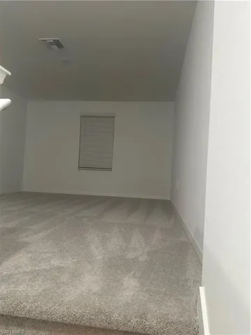 Wall-to-wall carpeting in a neutral tone, complete with window blinds and a ceiling-mounted light fixture