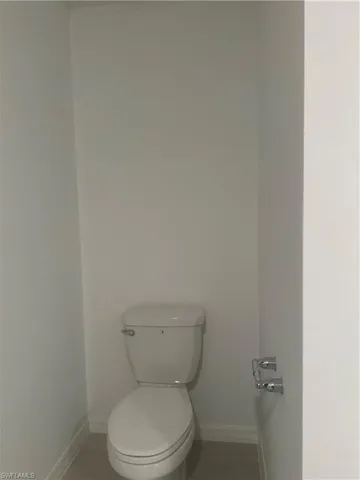 White porcelain toilet with chrome flush lever and a double-roll toilet paper holder