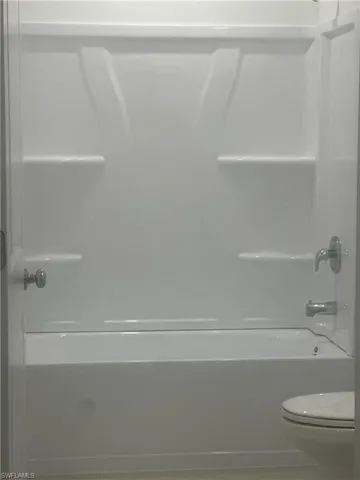 White tub/shower combination with integrated shelving and chrome fixtures