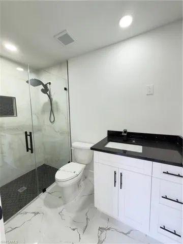 Full bath with vanity, a marble finish shower, and recessed lighting