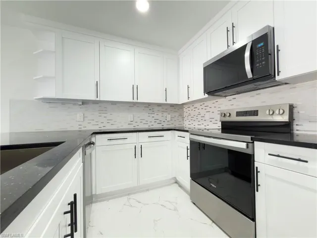 Kitchen featuring stainless steel appliances, open shelves, and white cabinetry