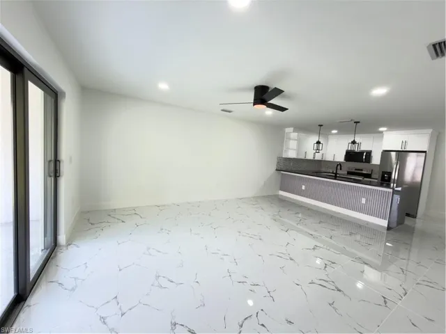 Kitchen with open floor plan, refrigerator, a ceiling fan, and white cabinets