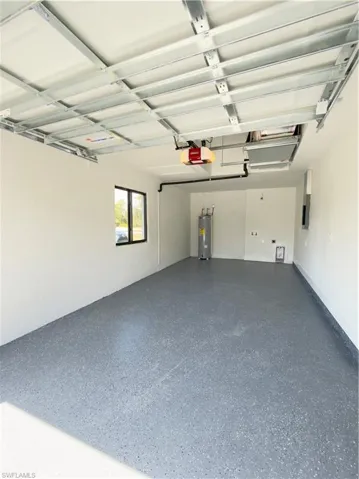 Garage featuring water heater, electric panel, and a garage door opener