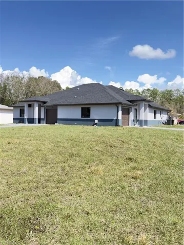 View of front of house featuring stucco siding, a front yard, and an attached garage