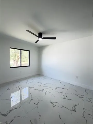 Unfurnished room featuring a ceiling fan and light marble finish flooring