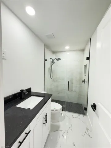 Bathroom featuring vanity, a marble finish shower, and recessed lighting
