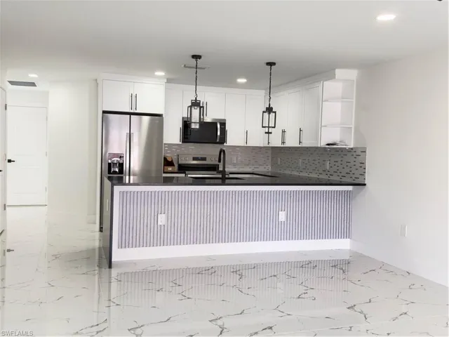 Kitchen with dark stone counters, a peninsula, open shelves, white cabinets, and range