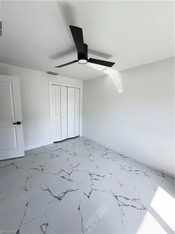 Unfurnished bedroom featuring a closet, a ceiling fan, and light marble finish flooring