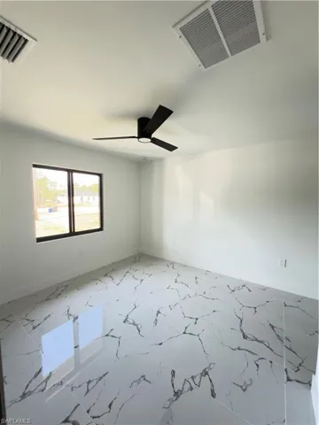 Spare room with ceiling fan and light marble finish floors