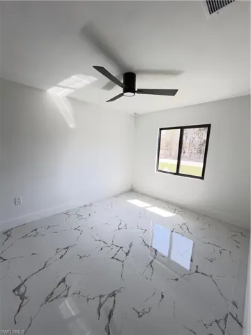 Spare room featuring light marble finish floors and ceiling fan