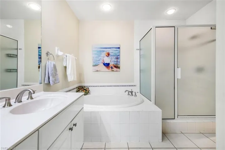 Primary bathroom featuring a bath, vanity, a shower stall, and light tile patterned flooring.