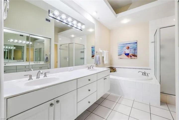 Primary bath with a garden tub, double vanity, a stall shower, light tile patterned floors, and recessed lighting.