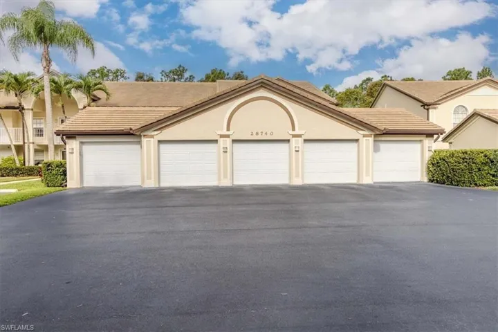 View of front of property with a tiled roof, community garages, and stucco siding