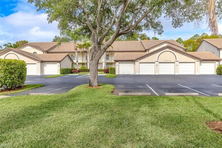 Ranch-style home featuring community garages, a front yard, and stucco siding