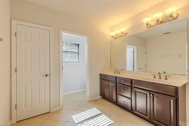 Full bath with double vanity and light tile patterned floors