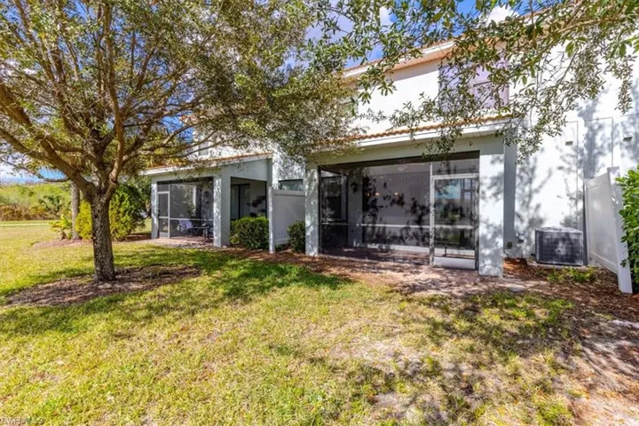 Rear view of property with stucco siding, a lawn, and a sunroom