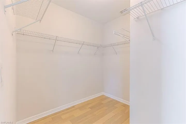 Walk in closet with light wood finished floors