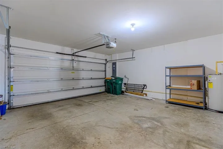 Garage featuring water heater, electric panel, and a garage door opener