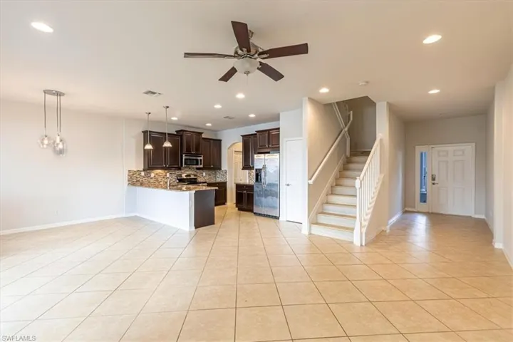Kitchen with dark wood finish cabinets, a peninsula, stainless steel appliances, backsplash, and a ceiling fan