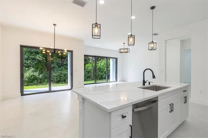 Kitchen island with a light-toned countertop, integrated sink, and dishwasher