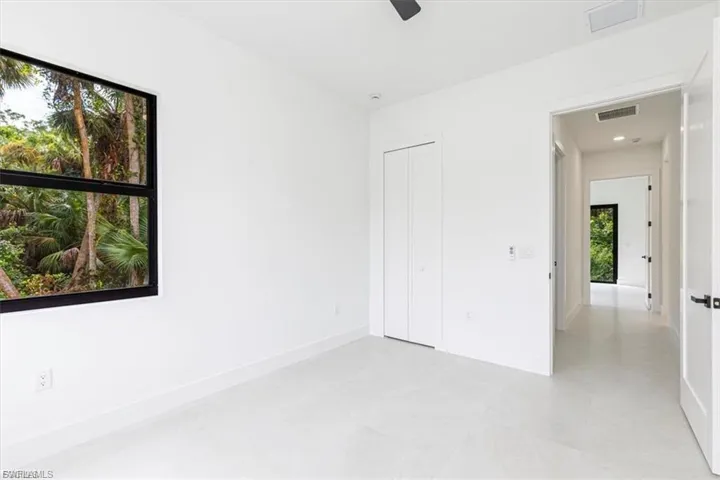 White interior walls, light-colored flooring, bifold closet doors, black framed window, recessed lighting